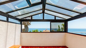 Una habitación con techo de vidrio, piso de baldosas rojas y vista al mar.