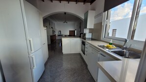 Una cocina moderna con armarios blancos, horno empotrado y pileta de acero inoxidable.