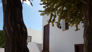 Una escalera que lleva a un edificio blanco con una puerta de madera y un ventanal pequeño.