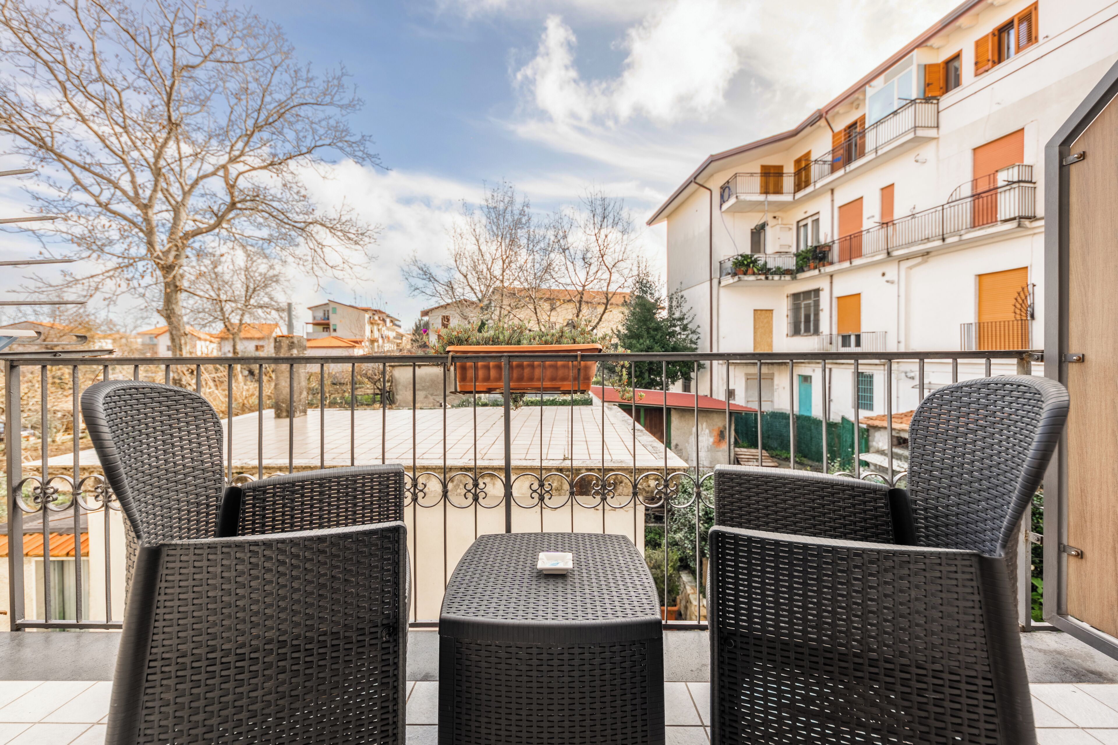 A balcony with wicker furniture and a view of a residential area.