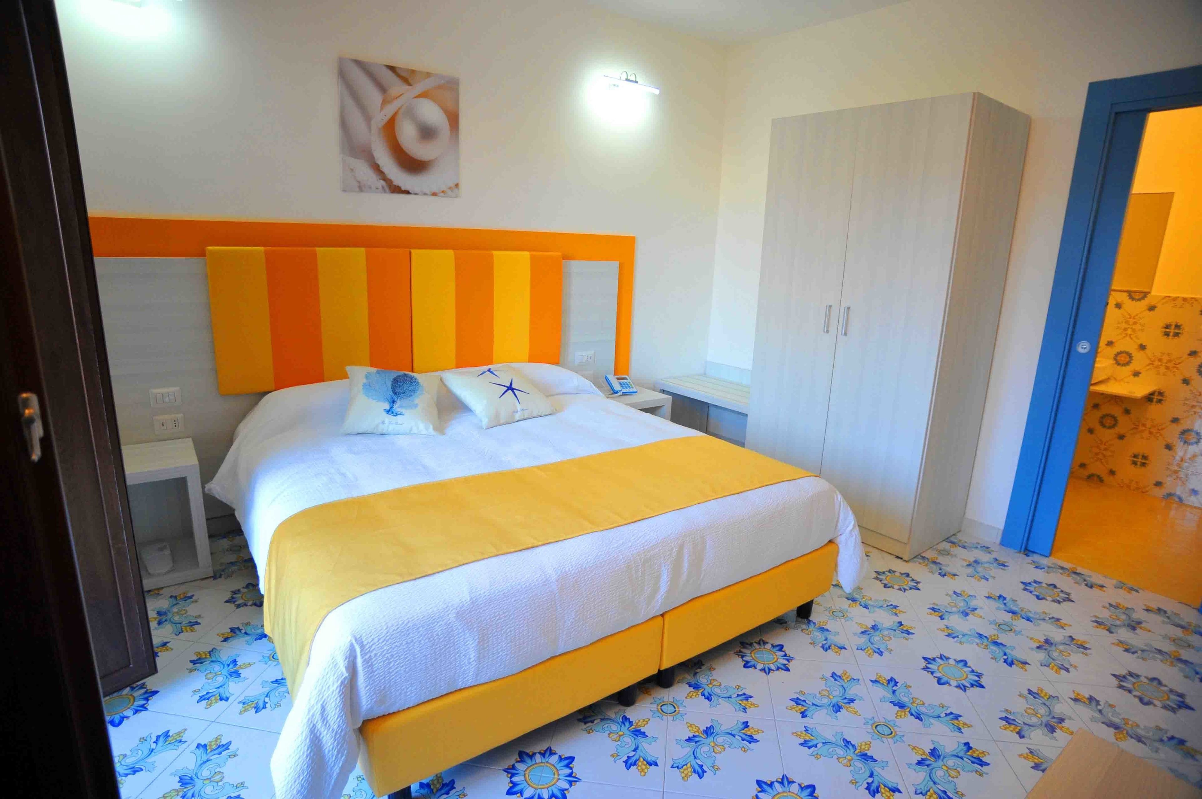 A bedroom with a bed, bedside tables, a wardrobe, and a patterned floor.