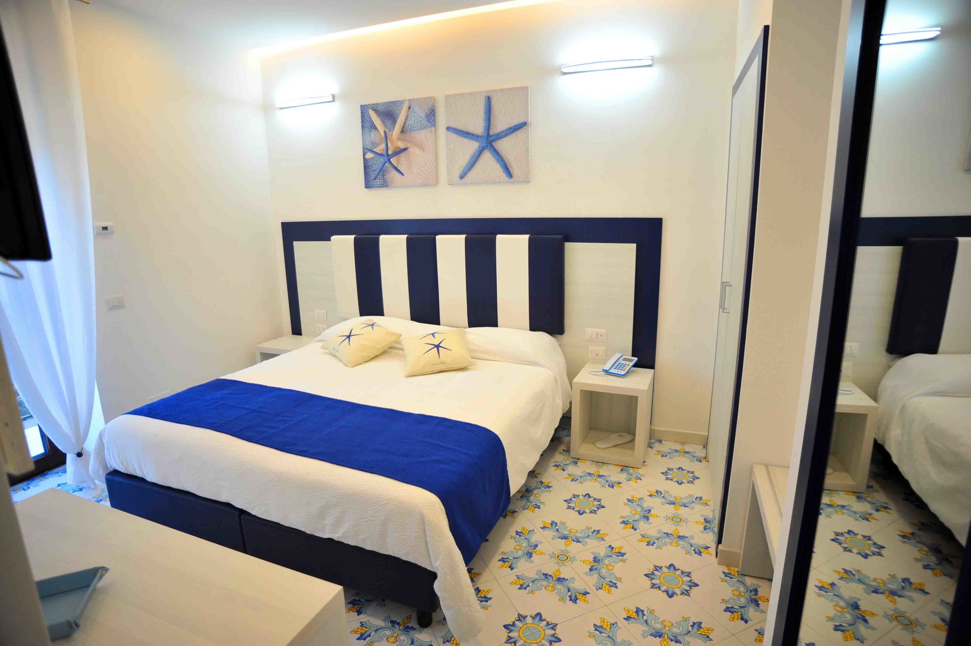 A hotel room with a bed, bedside tables, a telephone, and a mirror.
