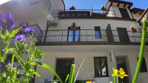 Un immeuble à deux étages doté de balcons, d’un espace extérieur aménagé pour s’asseoir et de plantes en pot.