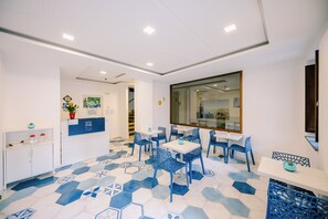 A modern dining area with hexagonal patterned flooring, white walls, and blue chairs. - Costa Blu (Agerola)