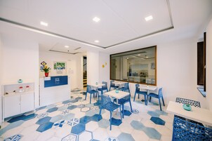A modern dining area with hexagonal patterned flooring, white walls, and blue chairs.