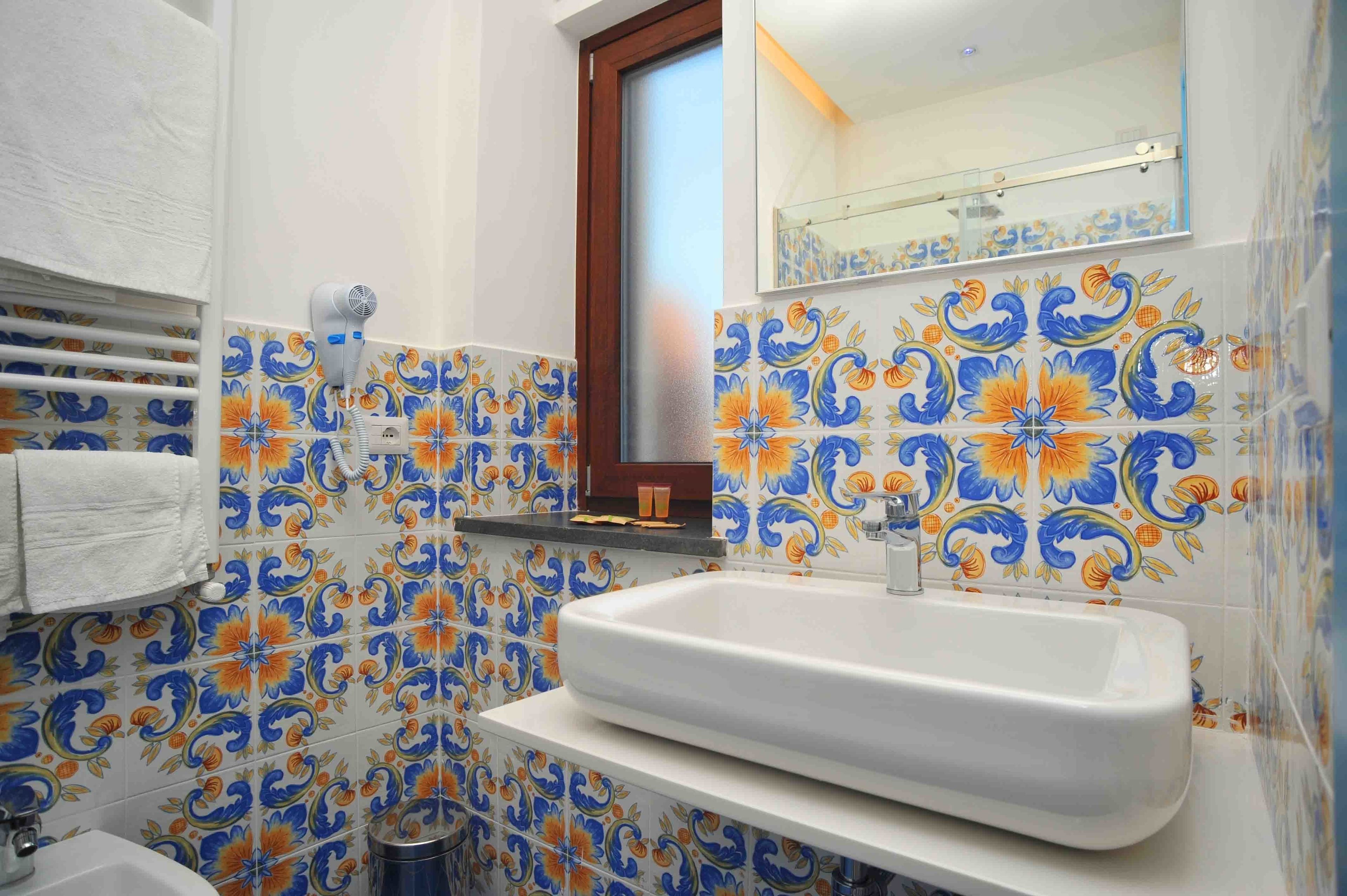Un baño con lavamanos blanco, toallero y espejo.