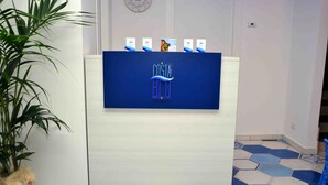 Un comptoir d’accueil avec une enseigne bleue portant l’inscription « COSTA BLU » et un pot de fleurs placé à gauche.