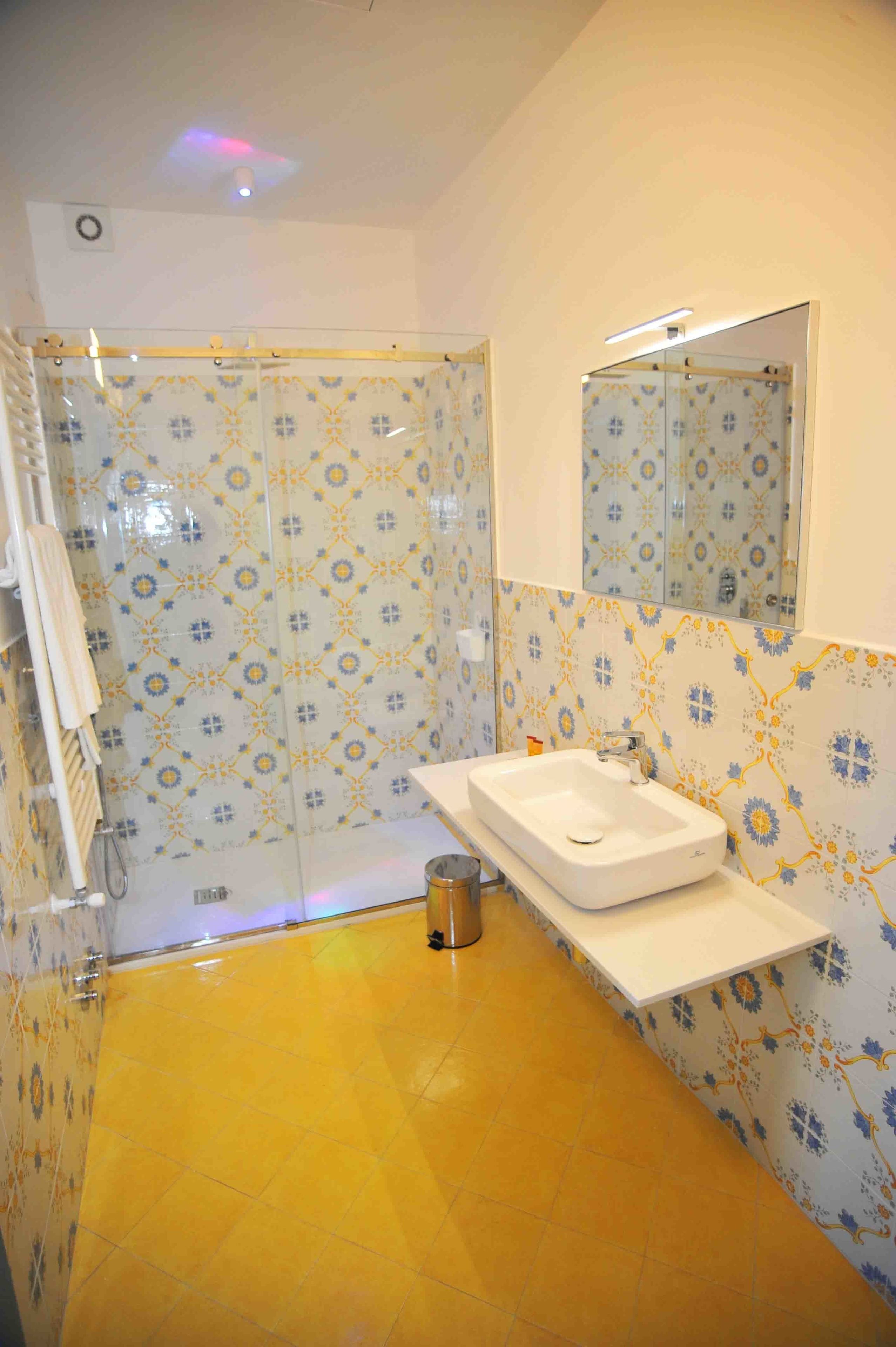 Un baño con baldosas estampadas, un lavamanos blanco y un espejo.