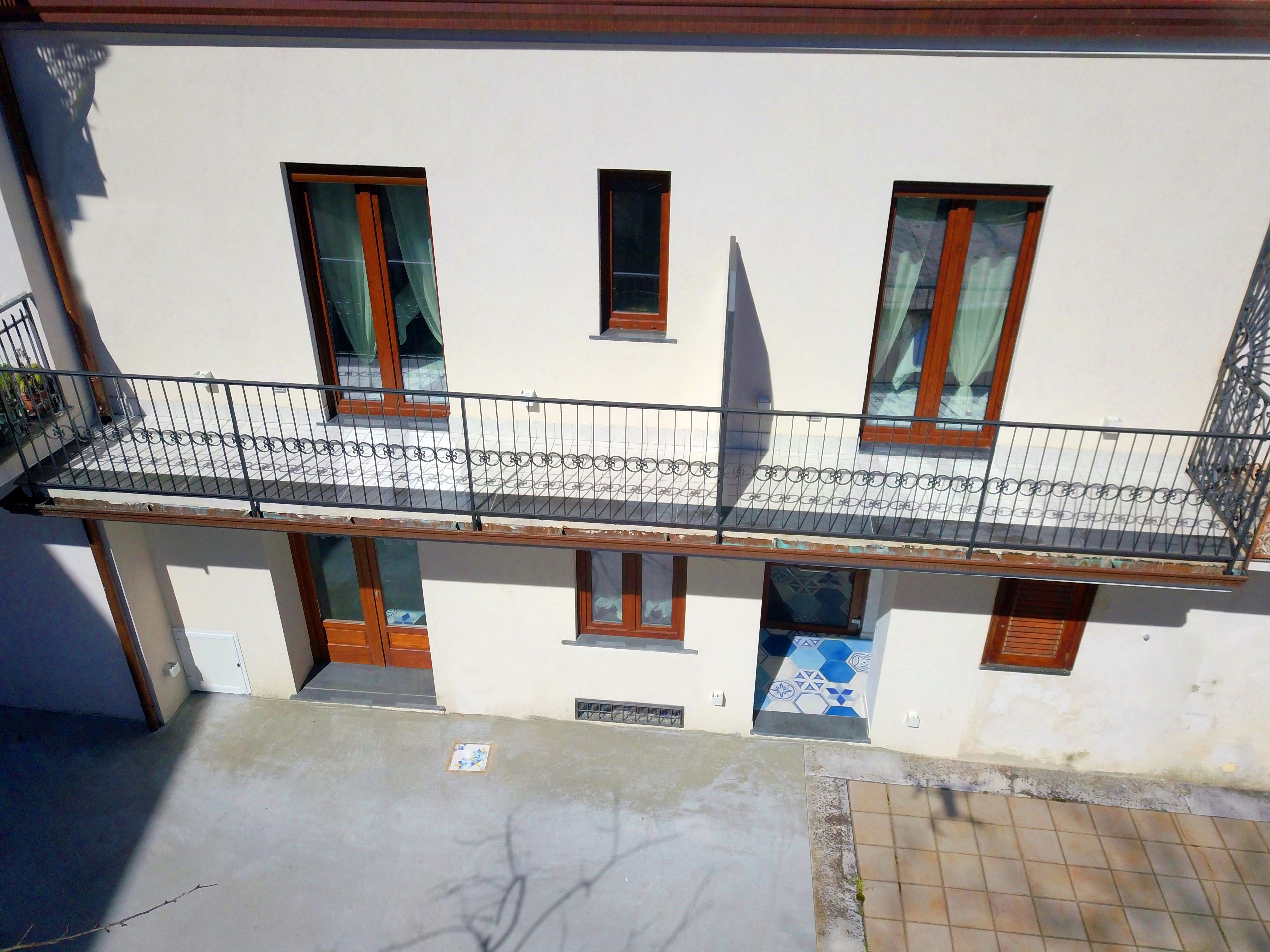 A multi-story building with a balcony, windows, and a tiled ground floor.