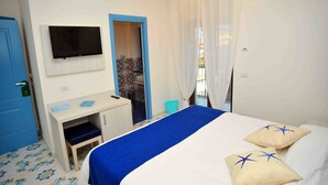 Une chambre d’hôtel avec un lit, un bureau, une télévision et une salle de bain, le tout visible à travers une porte ouverte.