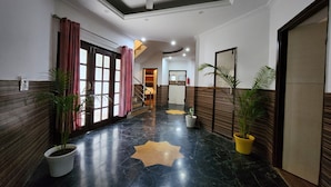 A hotel lobby with a marble floor, potted plants, a ceiling fan, and a star-shaped rug. - Hotel Bliss (Kasauli)