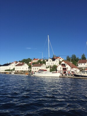 A coastal town with white buildings, a dock with boats, and a clear blue sky. - Idyllic southern country house in Risør (Risør)
