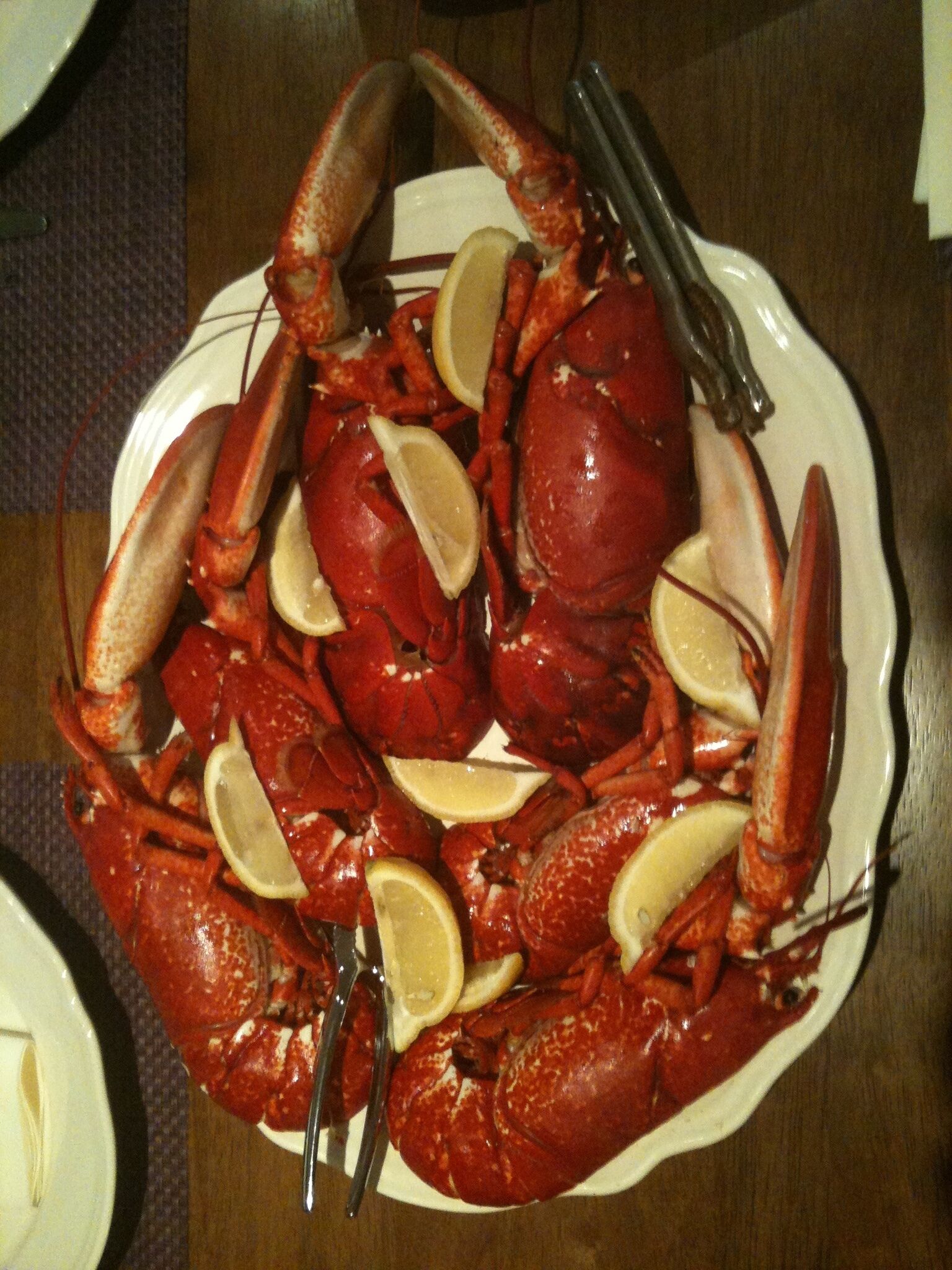 Une assiette d’écrevisses cuites, garnie de tranches de citron, sur une assiette blanche.
