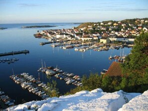 Une ville côtière dotée d’un port de plaisance rempli de bateaux, entourée d’immeubles résidentiels et de verdure.