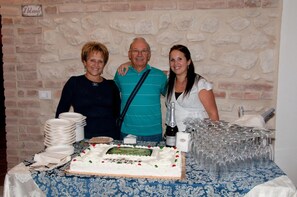 A table with a cake, plates, and glasses, set against a brick wall. - Il Poggio Dei Pettirossi (Pettorano sul Gizio)