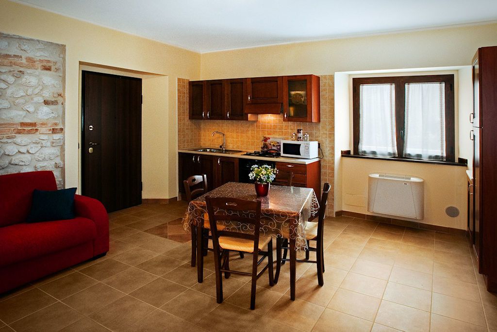 A compact living space with a kitchen, dining area, and a red sofa.