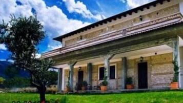 Un edificio tradicional con un porche cubierto y columnas, rodeado de vegetación.