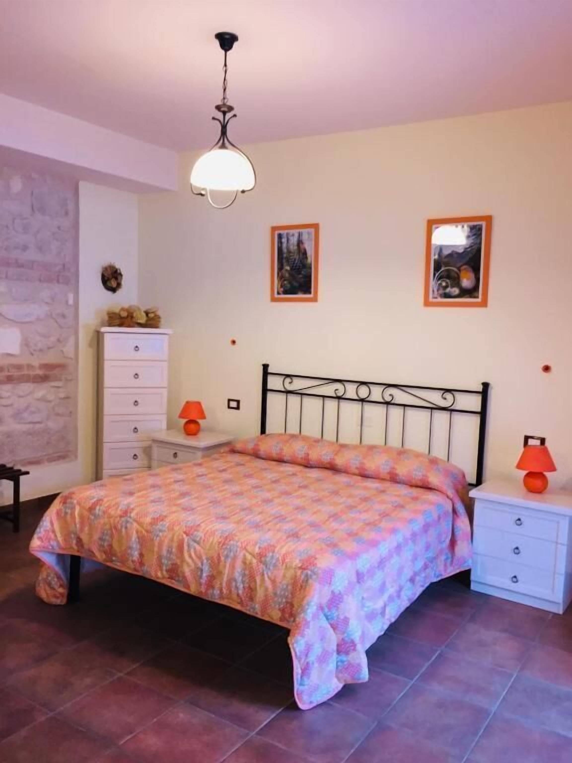 Una camera da letto con un letto, comodini, una cassettiera e due quadri appesi al muro.