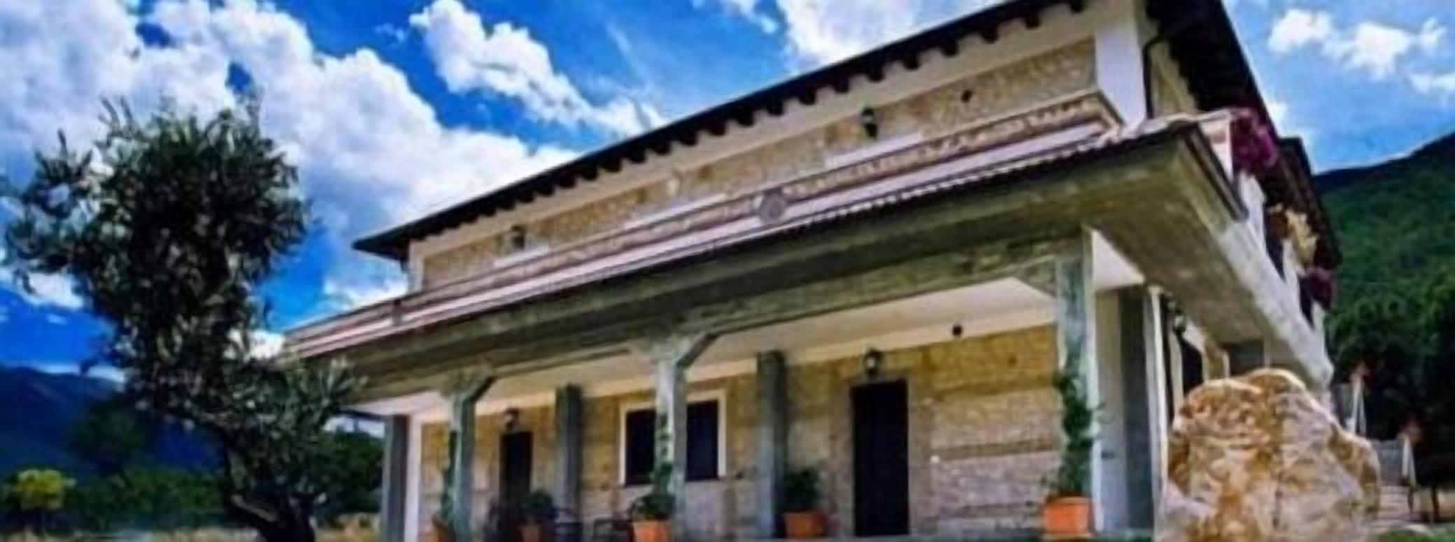 A two-story building with a central courtyard, columns, and a stone facade.