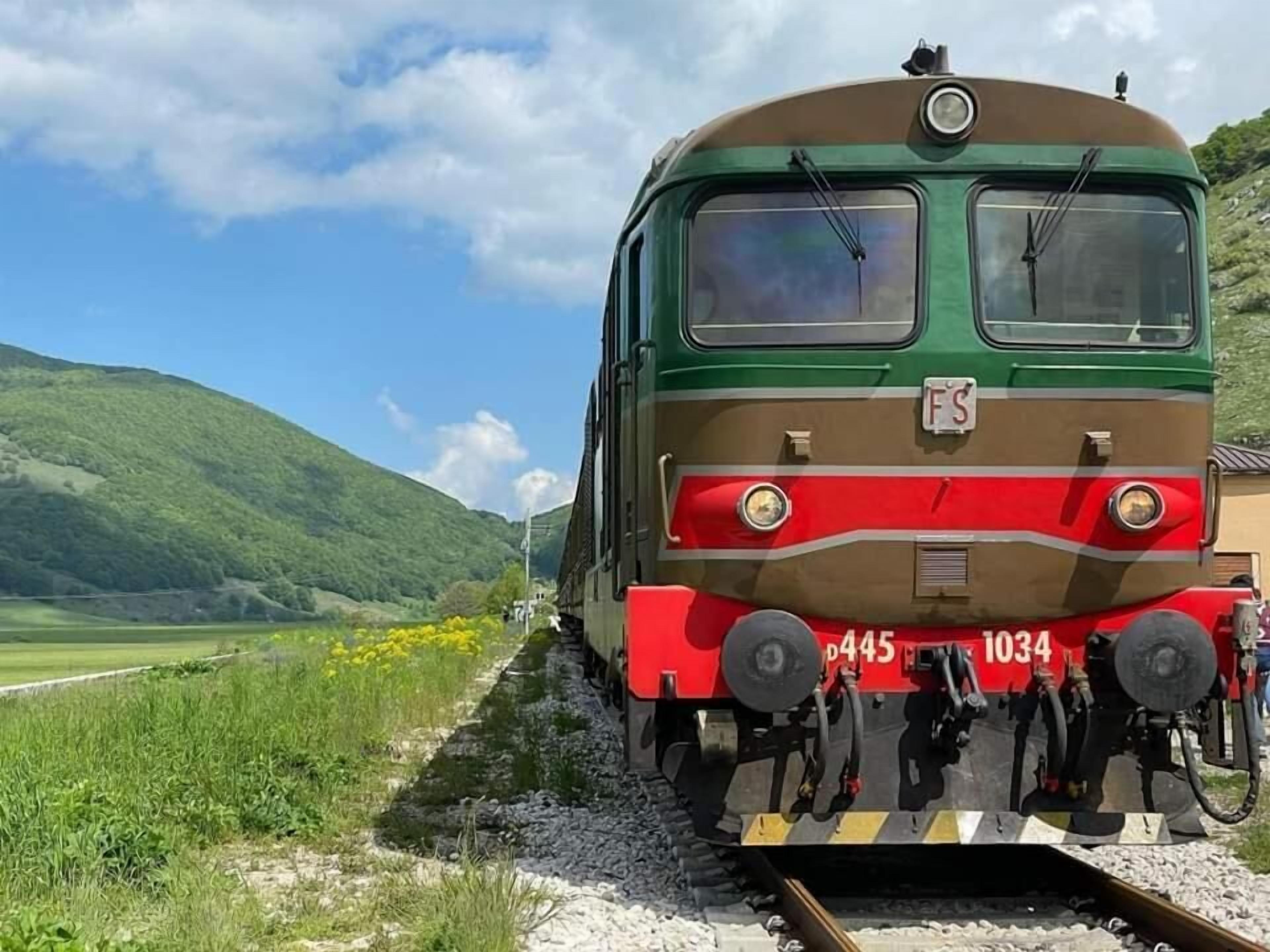 A train on tracks with a mountainous landscape in the background.