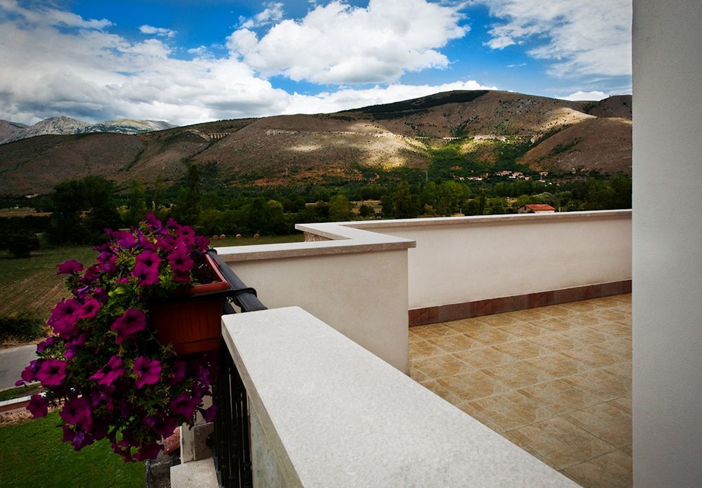 A balcony with a view of mountains and a hanging flower pot.