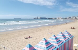 A beach with a pier in the background, a sandy shore, and a colorful building in the foreground. - Amazing home in Olonne sur Mer with WiFi (Olonne sur Mer)