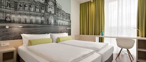 Habitación de hotel con dos camas, un escritorio, una silla y un mural grande de un edificio histórico.