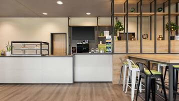 A modern kitchen with a central island, bar area with stools, and wooden shelving with decorative items.