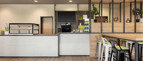 A modern kitchen with a central island, bar area with stools, and wooden shelving with decorative items.