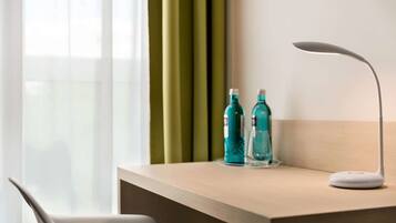 A desk with a modern lamp, two teal water bottles, and a wooden surface.