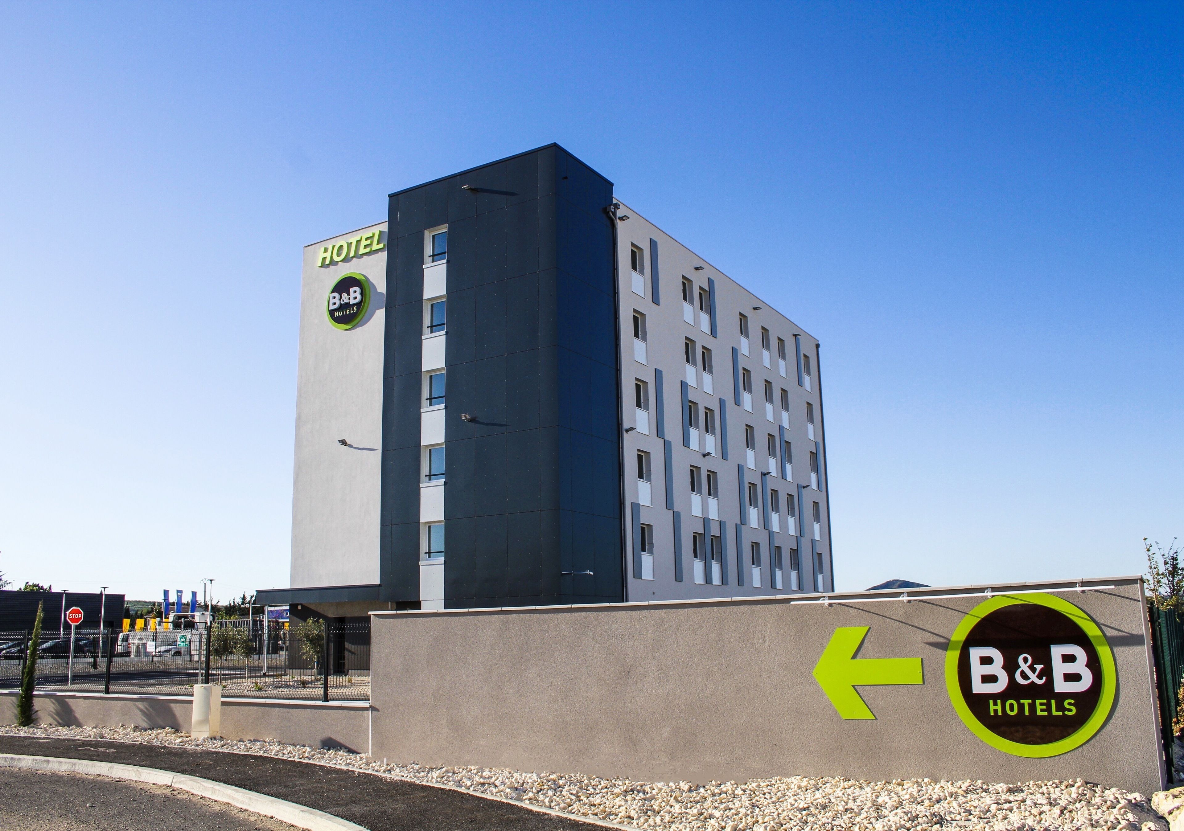 A B&B hotel with a modern design, featuring a prominent sign with an arrow pointing left.