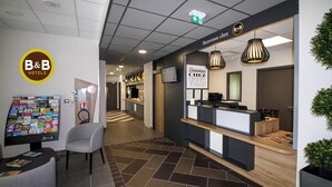 A reception area with a B&B logo, a reception desk, a seating area, and a directory board.