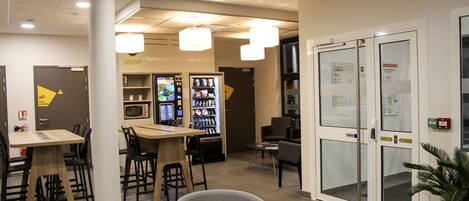 A modern interior with a dining area, a shop, and a reception desk.