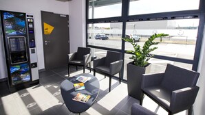 A reception area with a self-service kiosk, seating, and a large window with a view of the street.