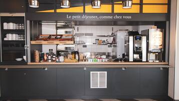 Un comptoir de café avec un tableau affichant le menu, une machine à café et divers produits alimentaires.