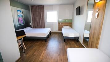 Habitación de hotel con dos camas individuales, un escritorio, una silla, un espejo y una ventana.