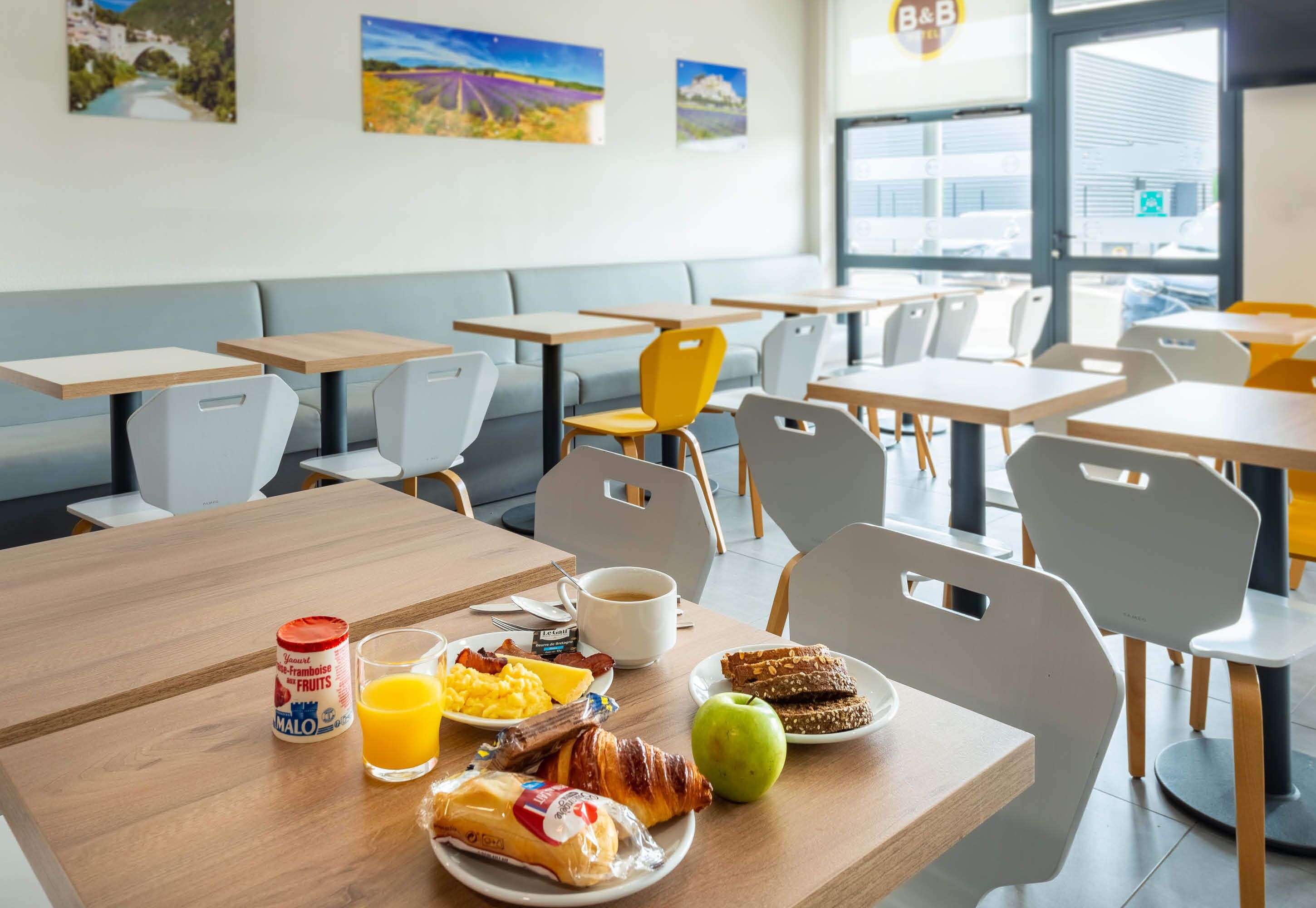 Une table mise pour le petit-déjeuner, avec des tables, des chaises et une variété d’aliments, notamment des œufs, des toasts et des fruits.