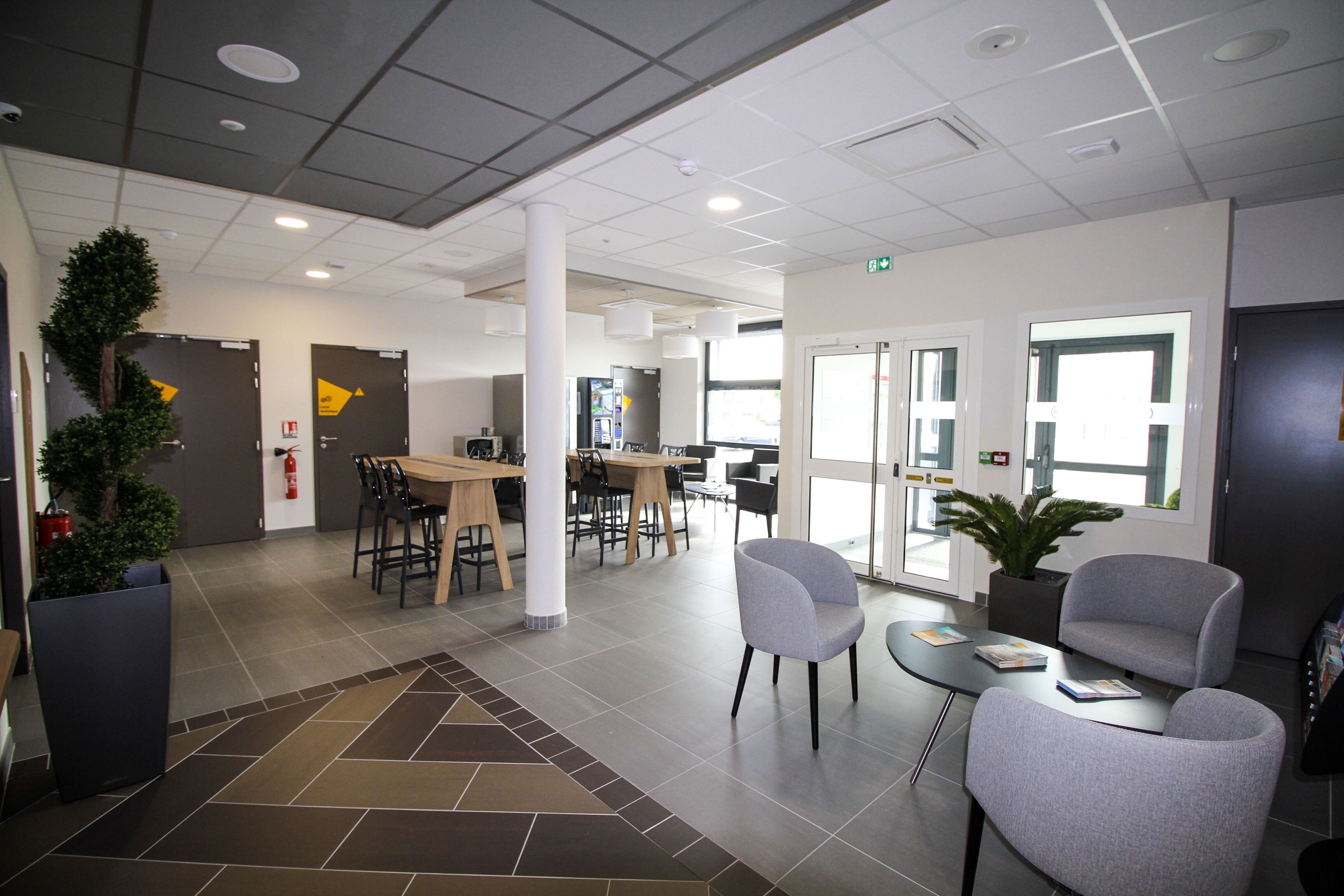 Un hall d’entrée moderne avec un comptoir d’accueil, un espace salon et une grande fenêtre.