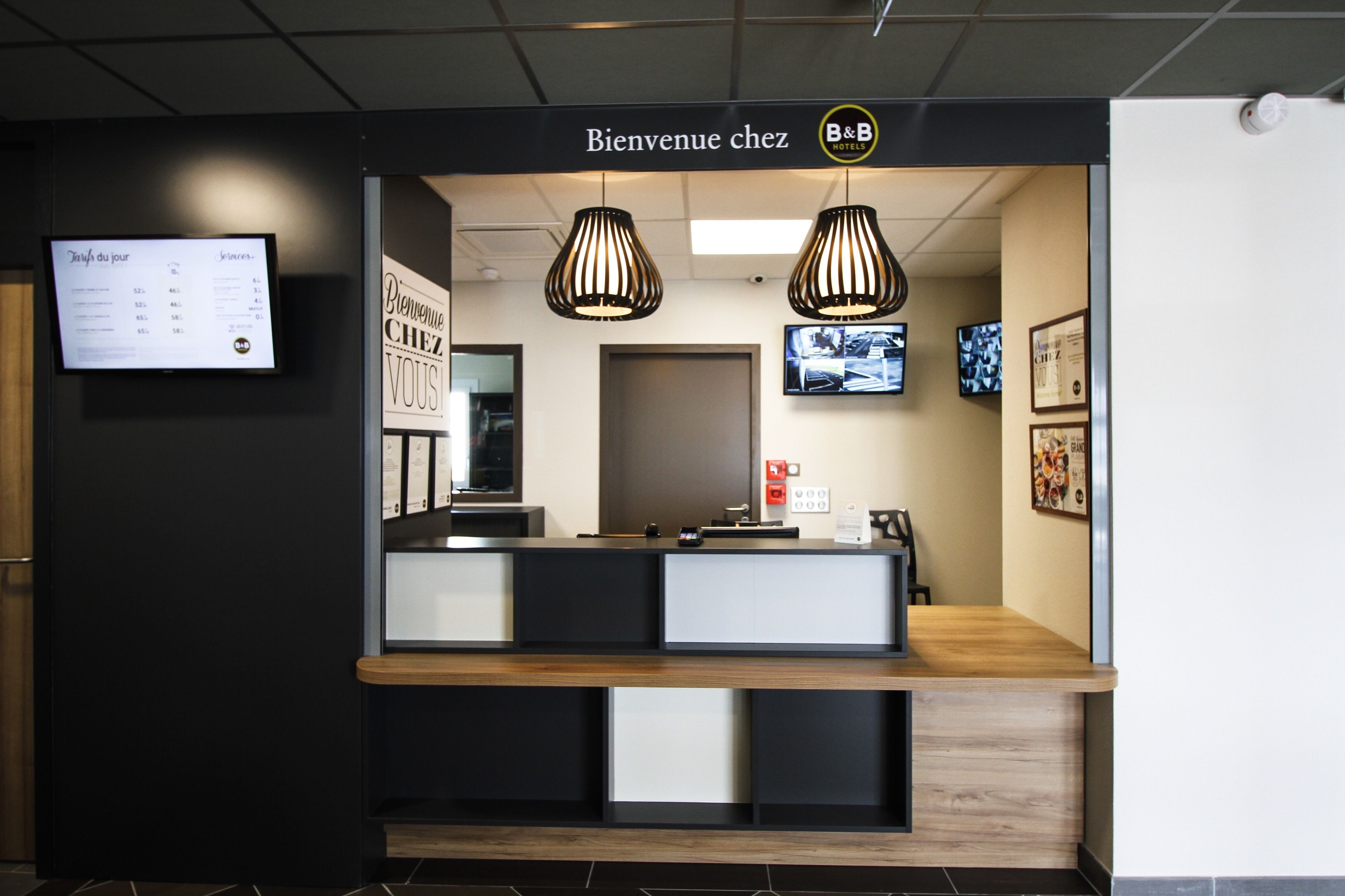 A reception desk with a sign reading "Bienvenue chez B&B HOTEL" and a menu board to the left.