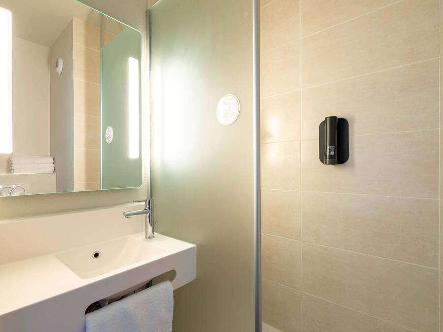 Ein modernes Badezimmer mit Waschbecken, Spiegel und einem an der Wand befestigten Händetrockner.