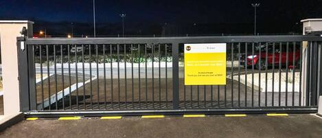 A gated parking area at night with a yellow sign on the gate.