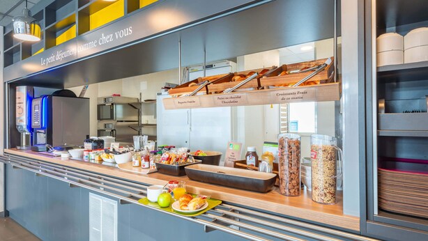 A breakfast buffet with labeled trays of bread, croissants, and pastries.