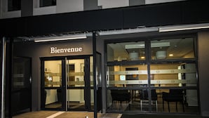 A restaurant entrance with a 'Bienvenue' sign, glass doors, and a view of the interior through the windows.