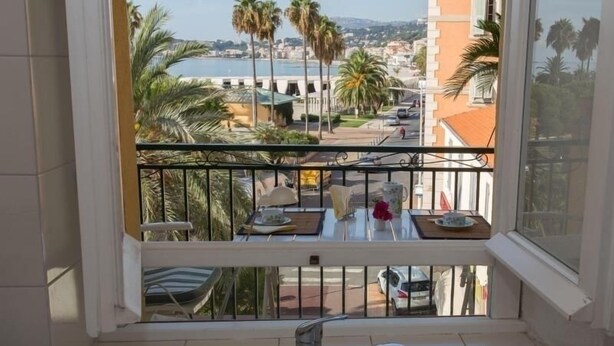 A balcony with a view of a coastal town, a table with chairs, and a sink. - Lovely 2P in Menton with sea view and terrace (Menton)