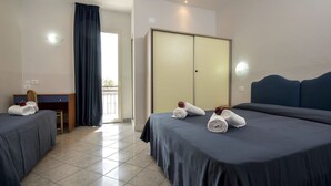 Ein Hotelzimmer mit zwei Betten, einem Schreibtisch, einem Kleiderschrank und Blick ins Freie.