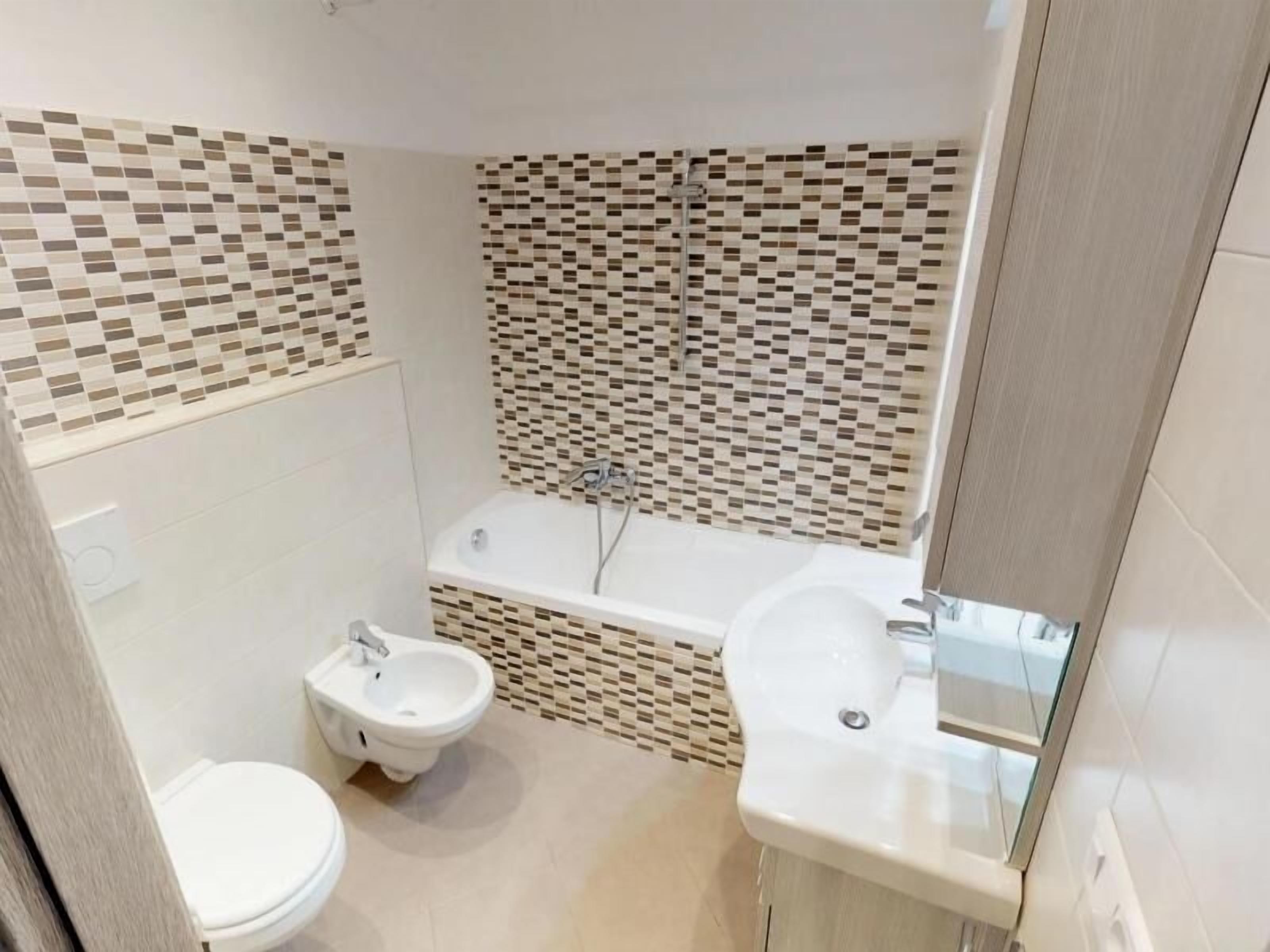 Une salle de bain comprenant des toilettes, un bidet, une baignoire et un lavabo.