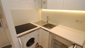Een functionele keuken met een ingebouwde kookplaat, gootsteen en wasmachine.