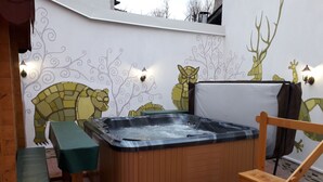 Un jacuzzi con un banco y una silla de madera, rodeado por una pared con murales de animales.
