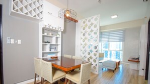 Un comedor con una mesa y sillas de madera, un estante blanco y una pared decorativa con diseños circulares.