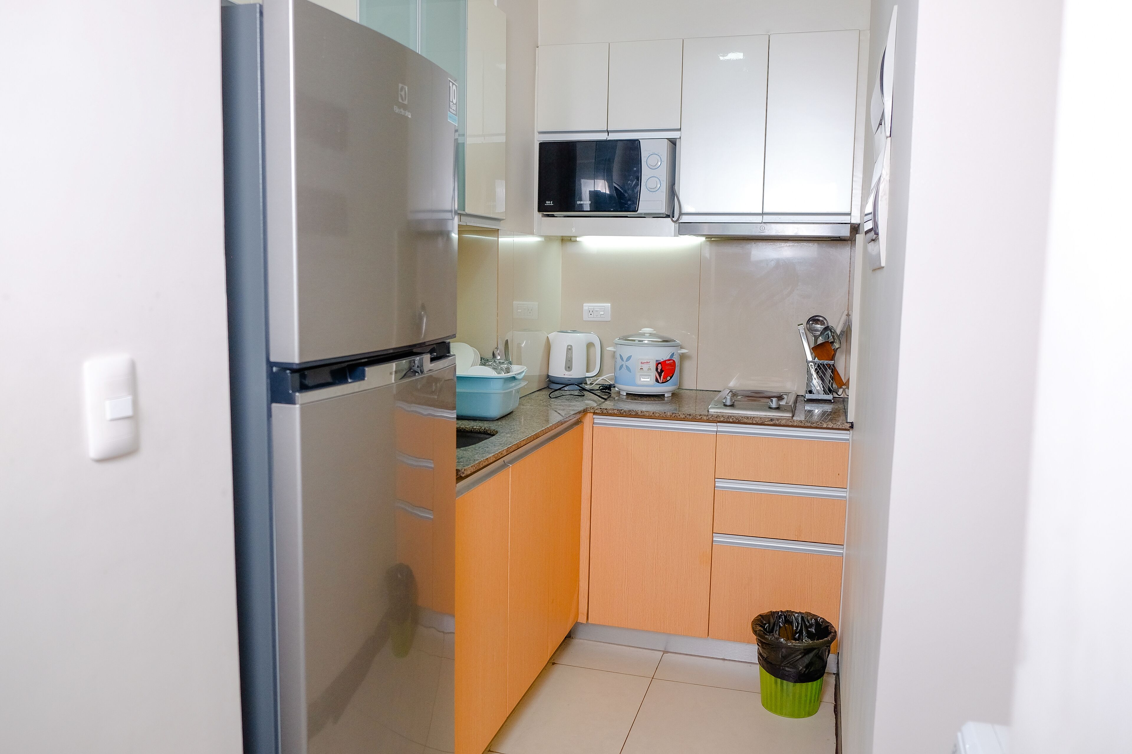 A compact kitchen with a refrigerator, microwave, and a sink.